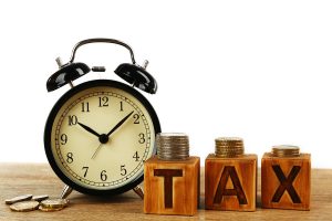 Tax time and alarm clock with coins on table